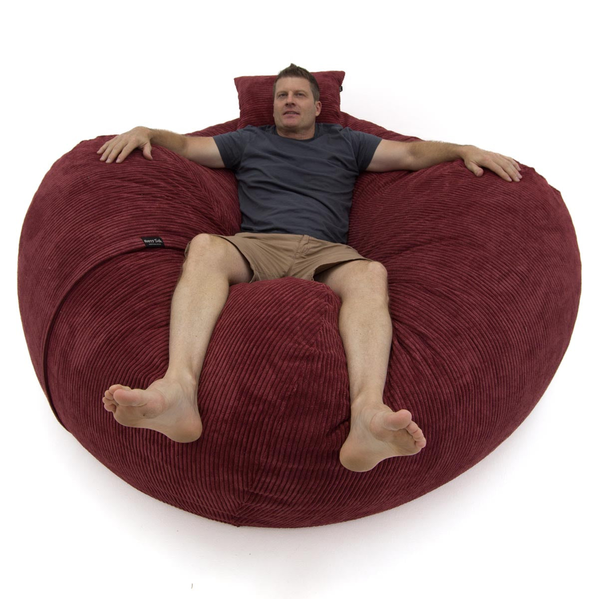 Man lying on a large red bean bag chair against a white background
