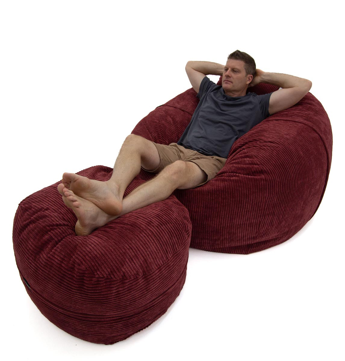 Man relaxing on a large red bean bag chair against a white background