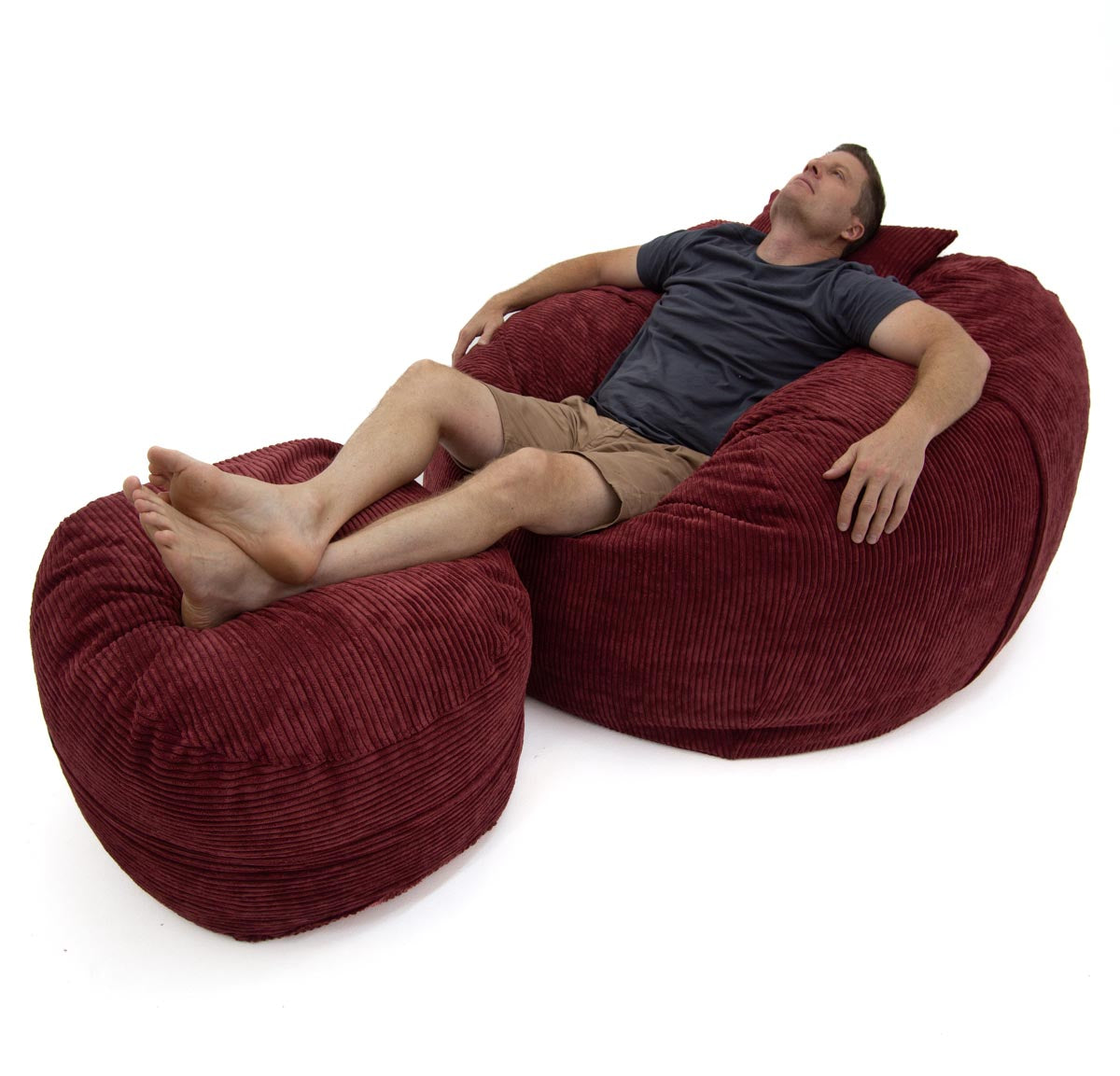 Man relaxing on a large red bean bag chair against a white background