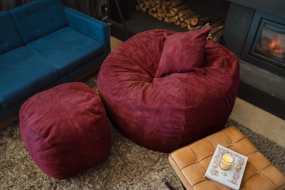 Red bean bags and a blue sofa in a cozy living room with a fireplace.