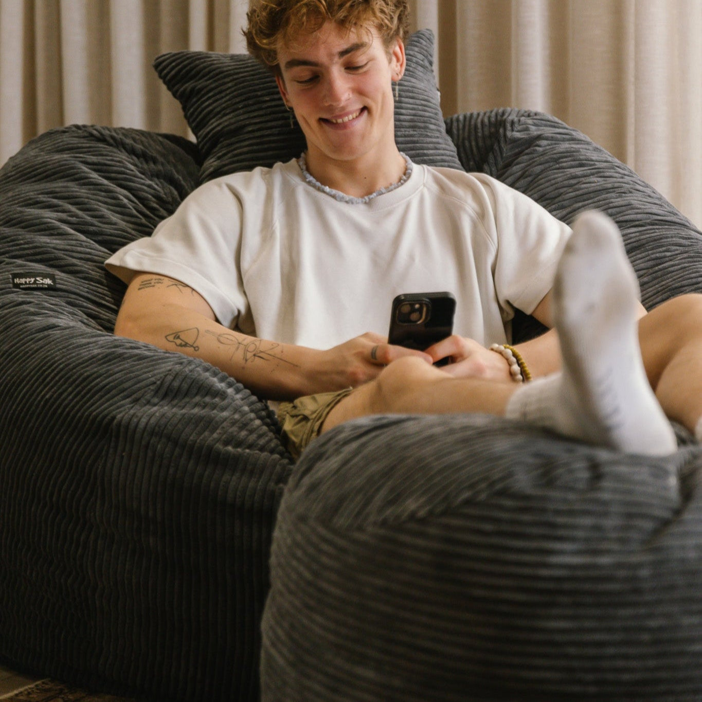 Man sitting on charcoal corduroy beanbag on his cell phone