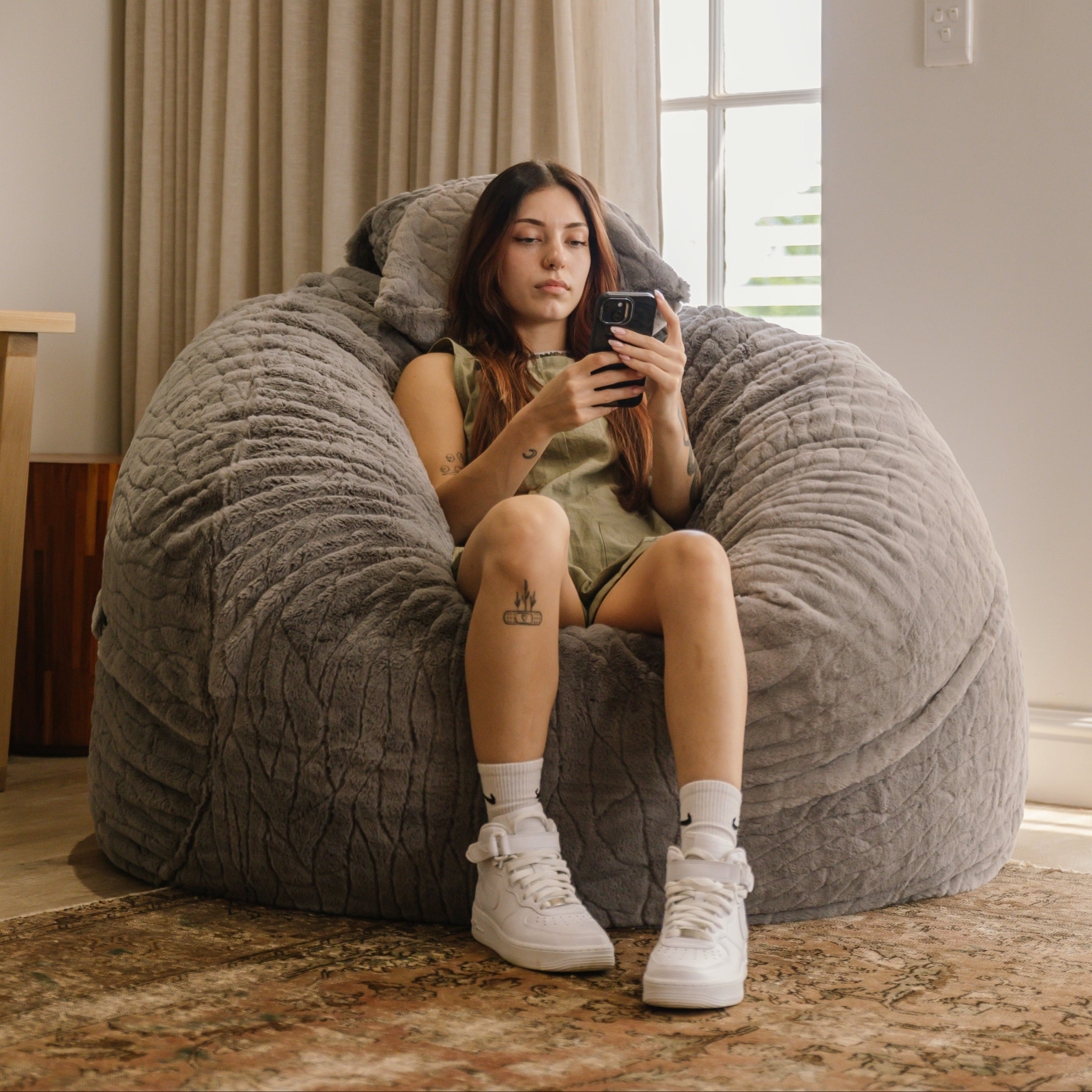 Woman using cell phone on large faux fur beanbag