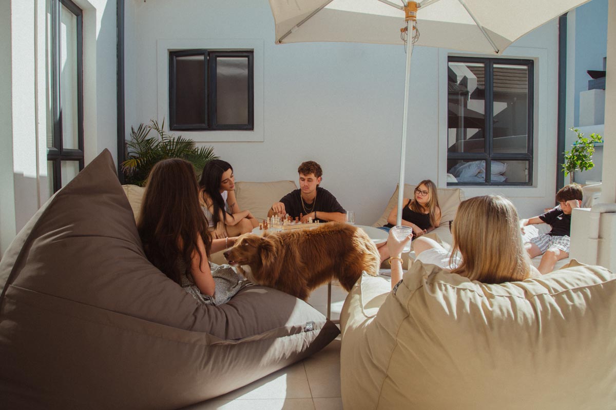 Group of people sitting on bean bags under an umbrella in a modern indoor setting.