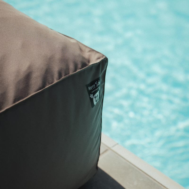 Gray bean bag chair with a brand logo by a pool