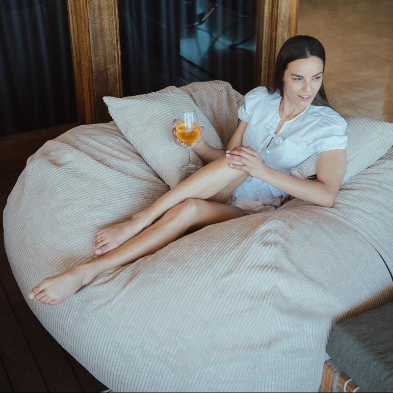 Woman sitting on a bean bag chair holding a glass of wine.