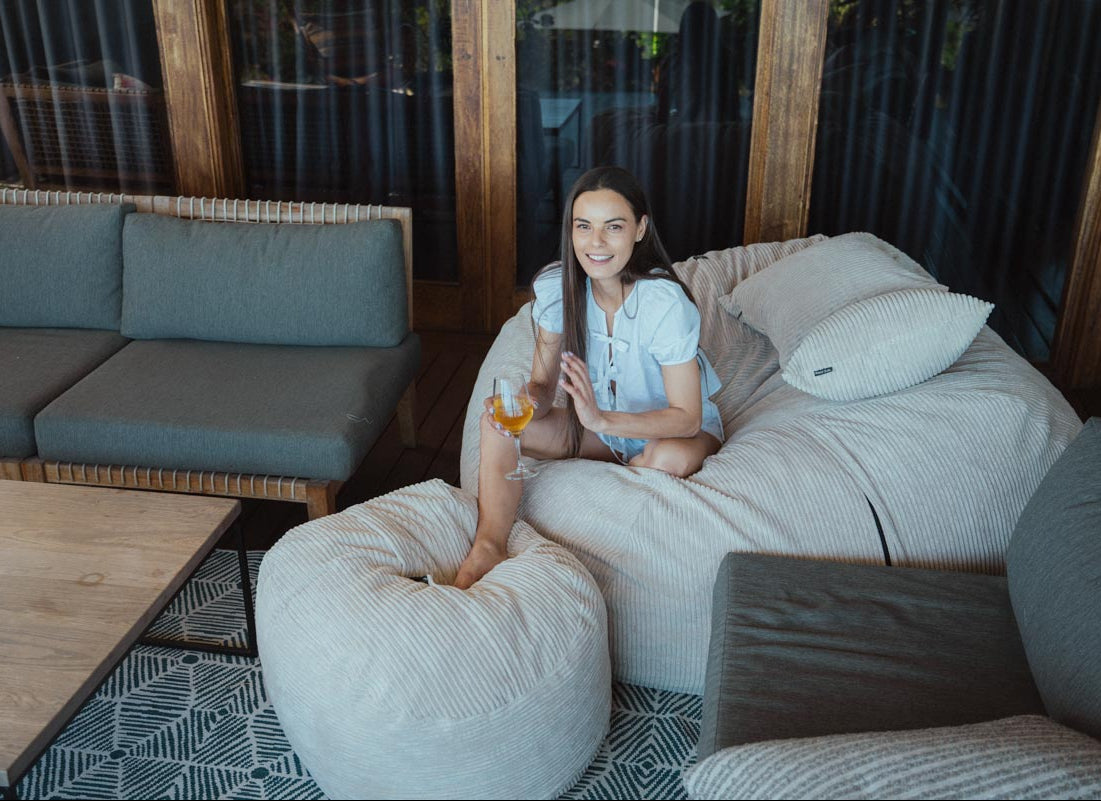 Woman sitting on a bean bag chair in a modern outdoor living space.