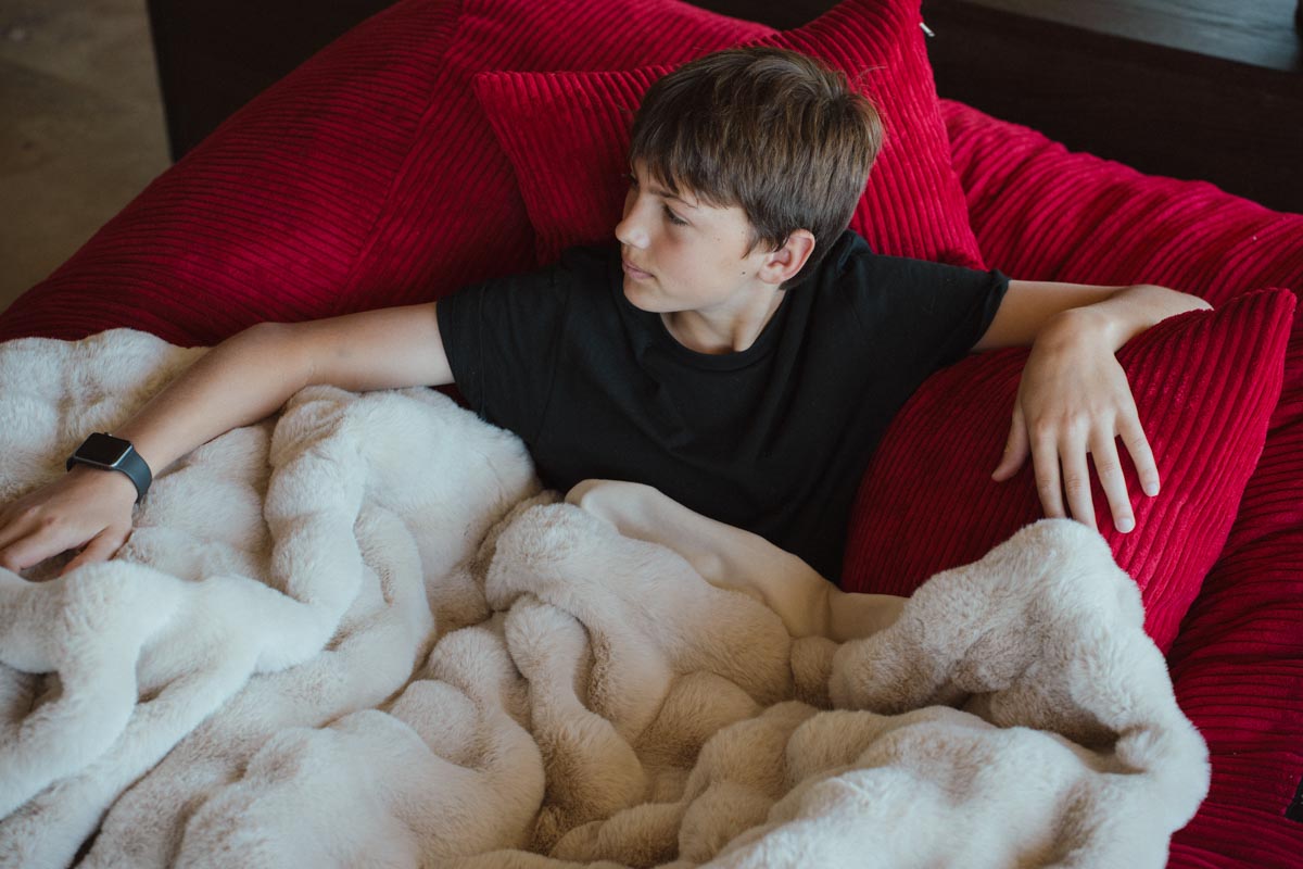 Person lying on a red couch with a white blanket