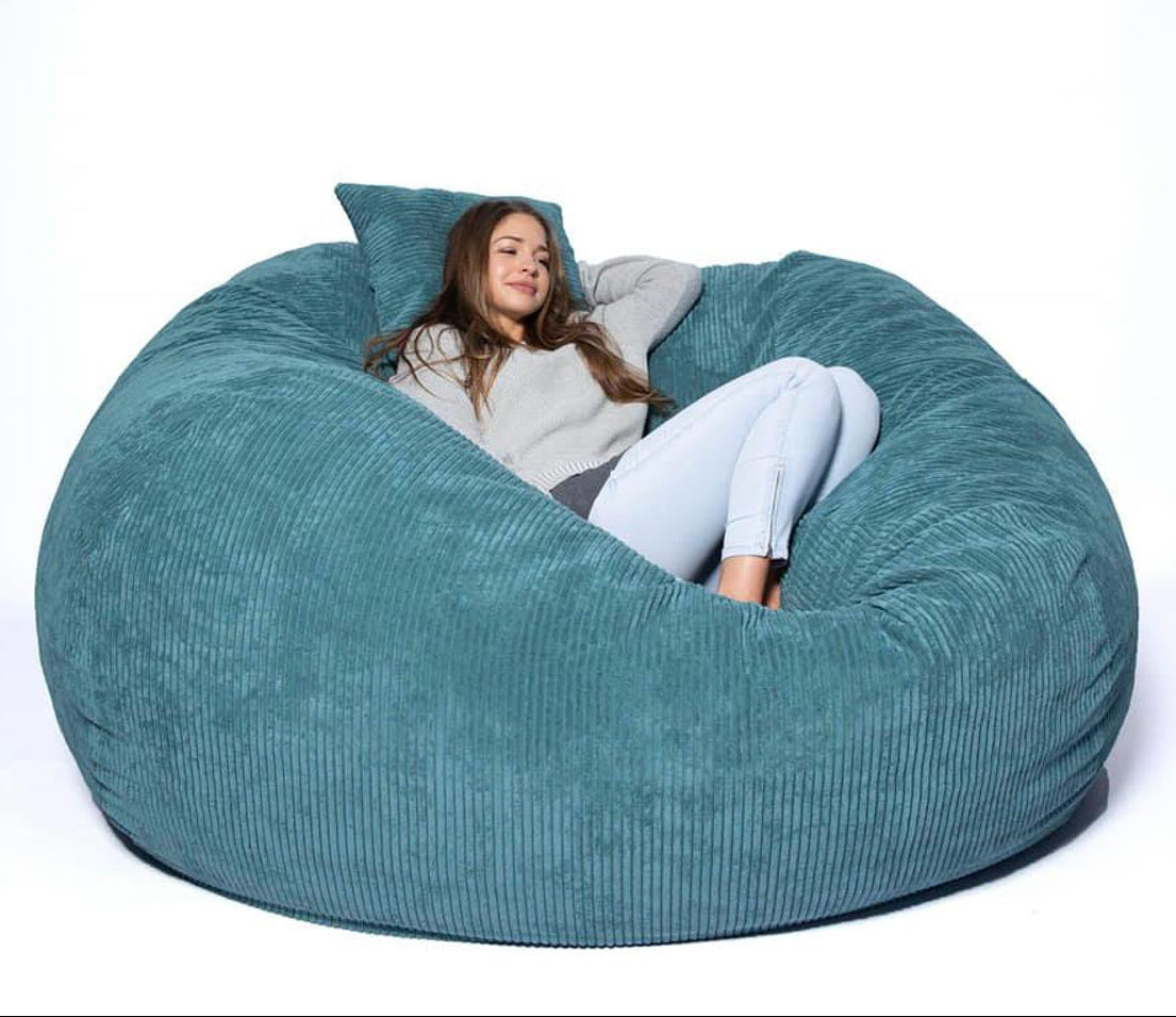 Woman sitting inside a large teal bean bag chair on a white background