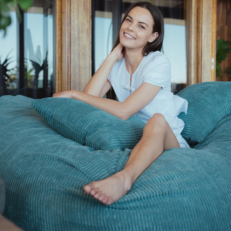 Woman sitting on a teal bean bag chair indoors