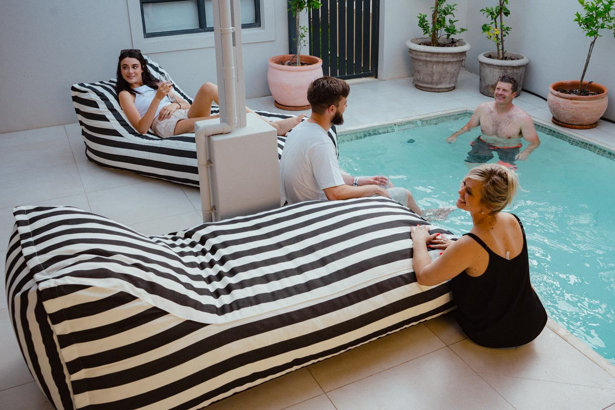 People relaxing by a pool with striped bean bags