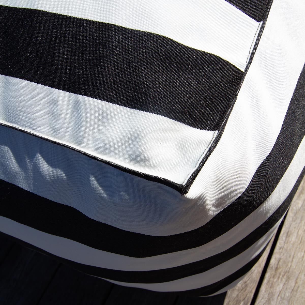 Close-up of a black and white striped fabric with a wooden surface in the background