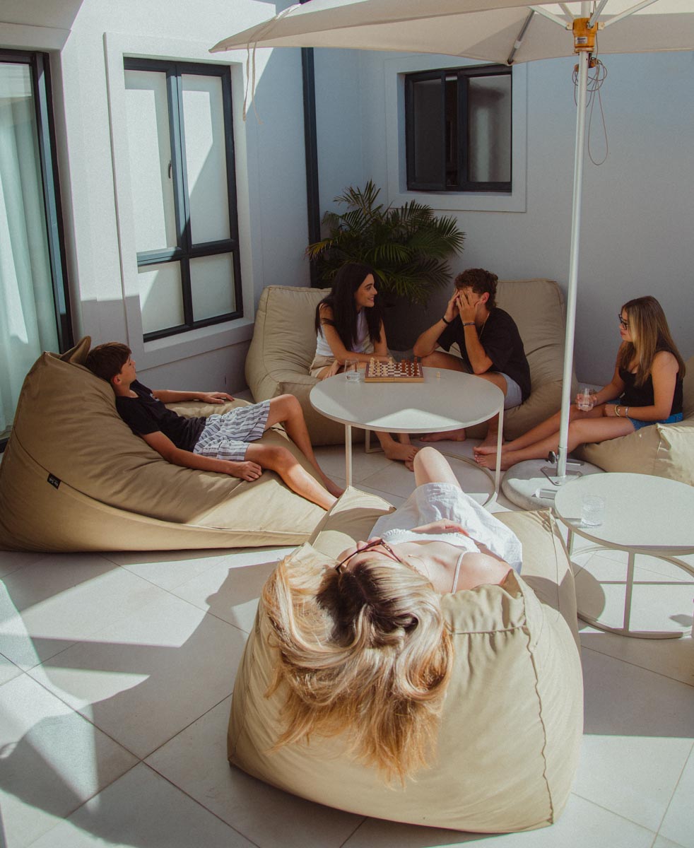 People relaxing on bean bags and a couch under an umbrella in a modern living room.