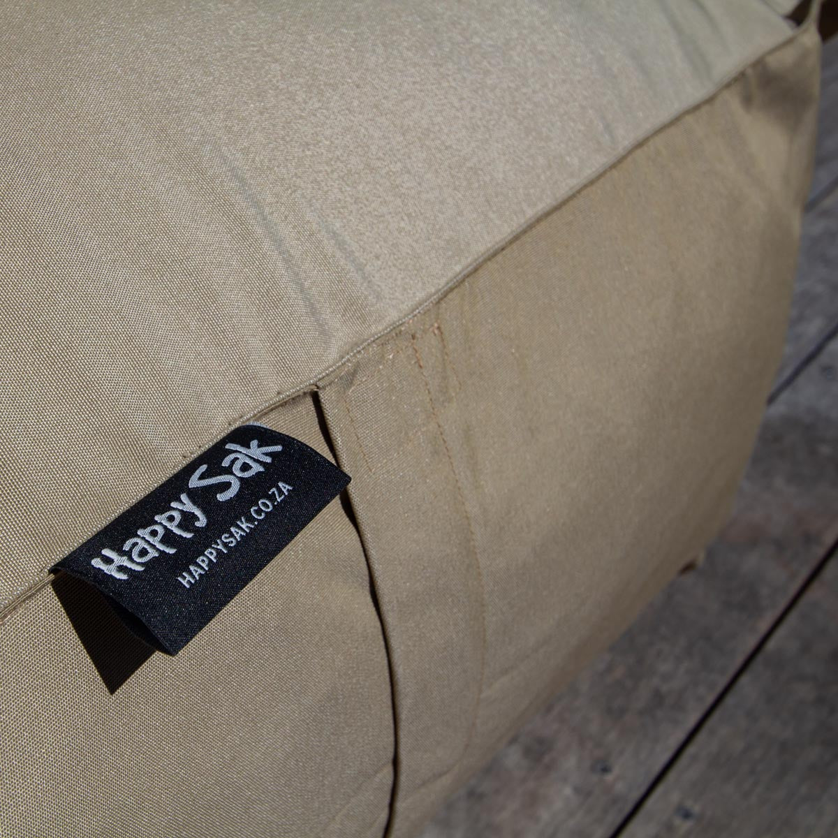Close-up of a beige bag with a 'Happy Sak' label on a blurred background