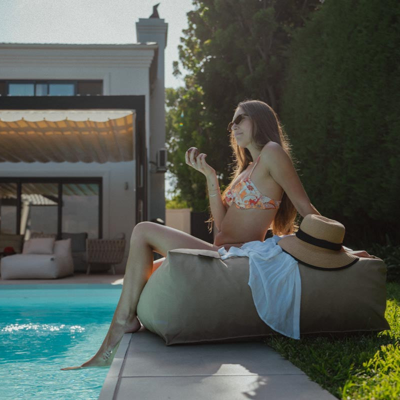 Woman sitting by a poolside with a scenic background
