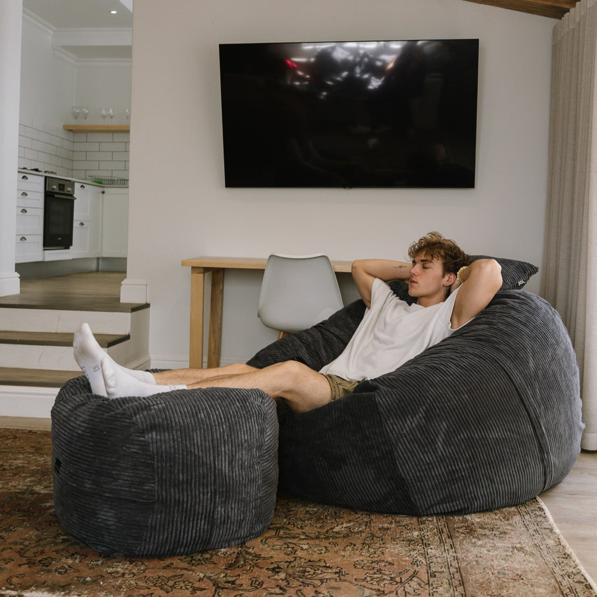 Man sitting on large charcoal corduroy beanbag