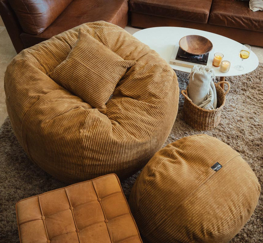 Brown bean bag chair and ottoman in a living room setting with a coffee table and decor items.