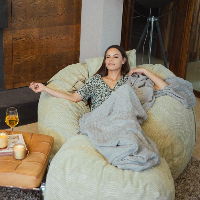 Woman relaxing on a bean bag chair in a cozy living room with a fireplace.