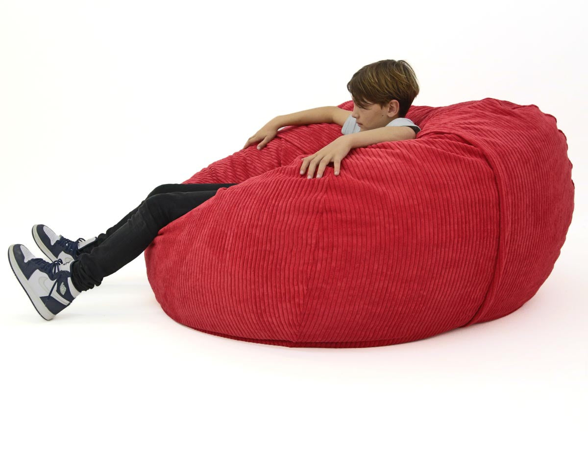Person sitting on a large red bean bag chair against a white background