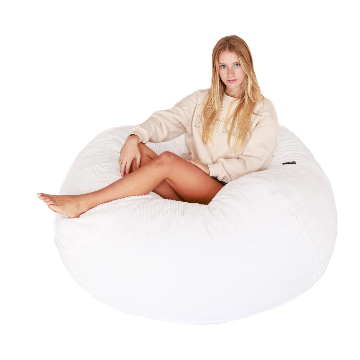 Woman sitting on a white bean bag chair against a white background