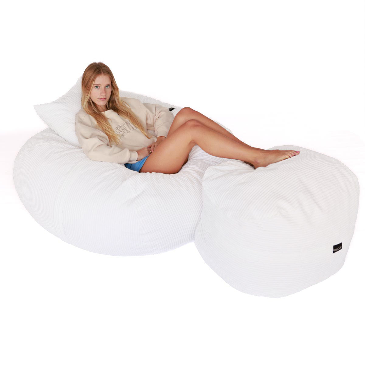 Woman sitting on a large white bean bag chair against a white background