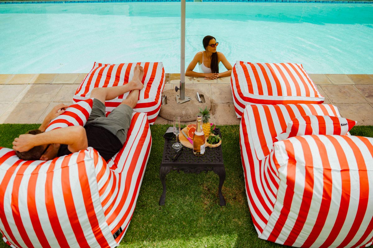 People lounging on red and white striped bean bags by a pool.
