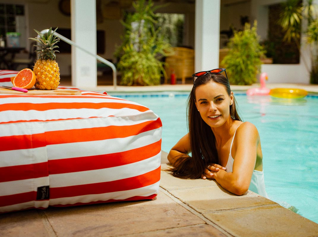 Woman by a pool with a pineapple and striped towel