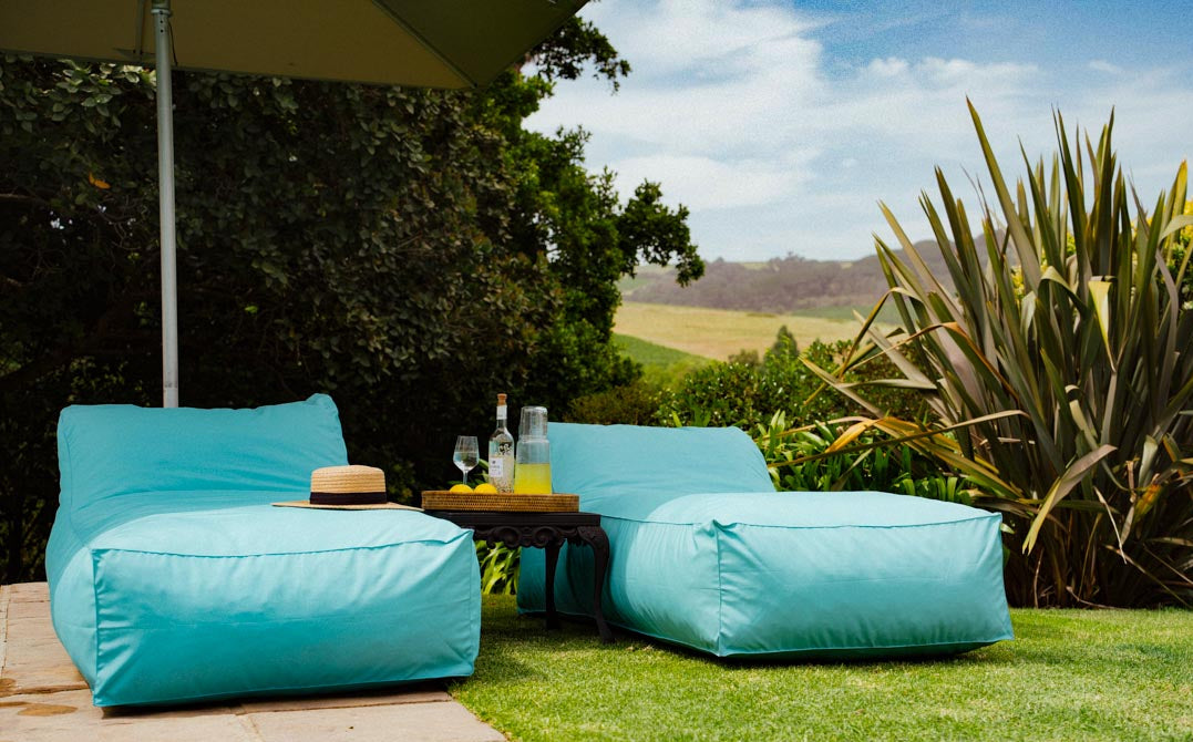 Turquoise outdoor furniture set on a grassy area with a scenic background