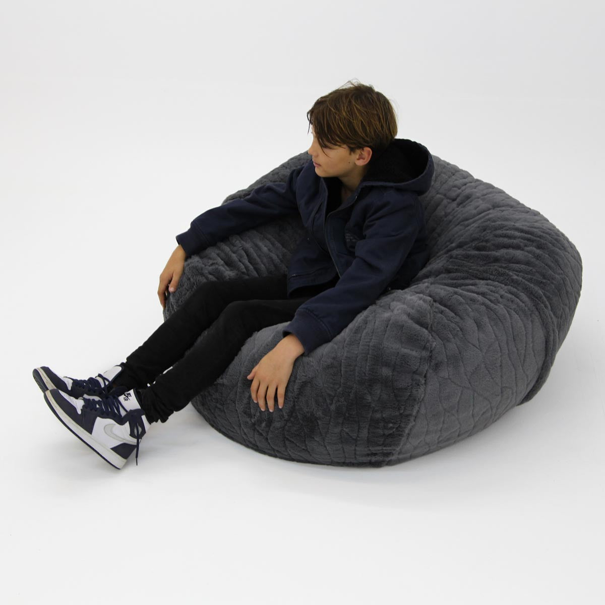 Person sitting on a large gray bean bag chair against a white background