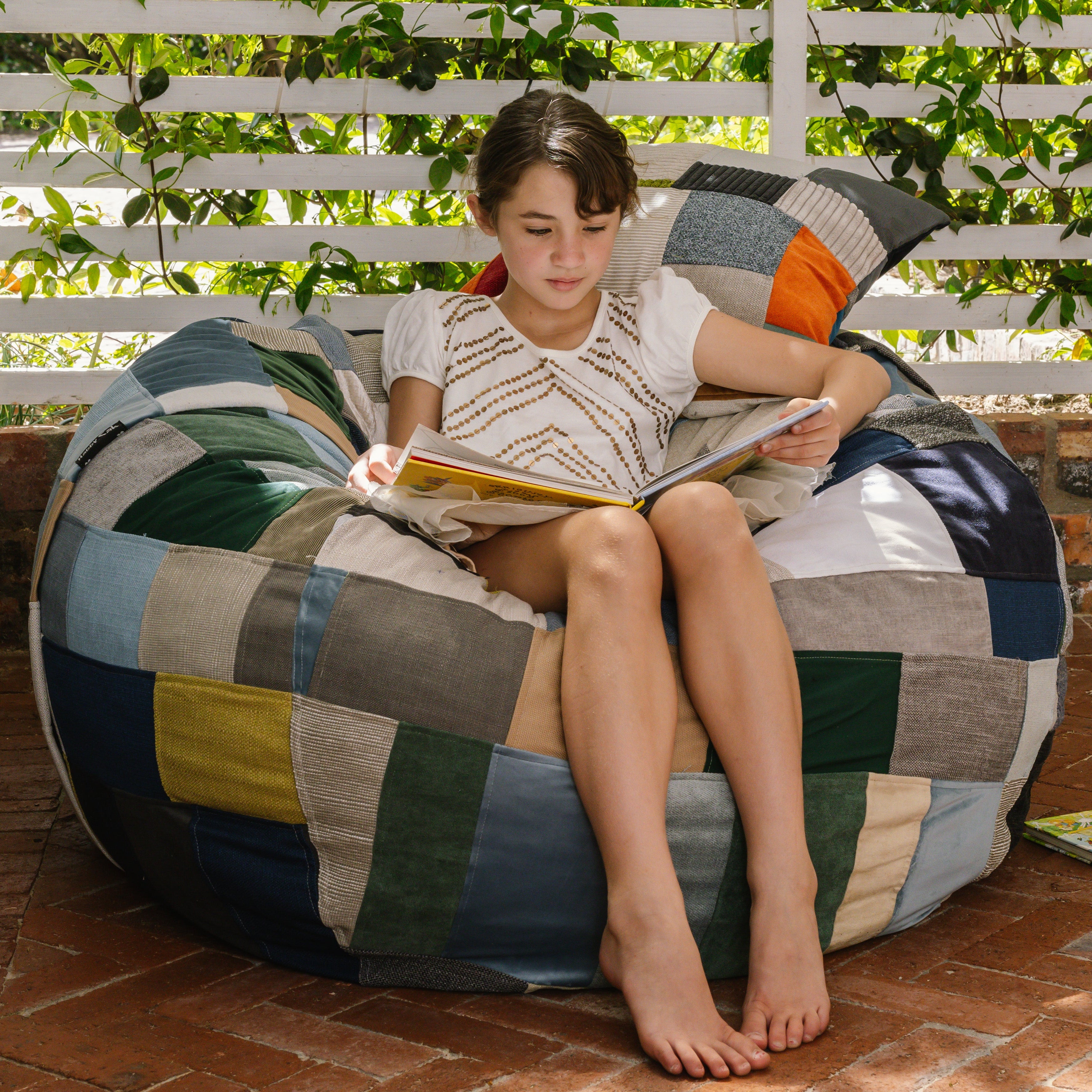 Girl sitting on patchwork beanbag reading a book