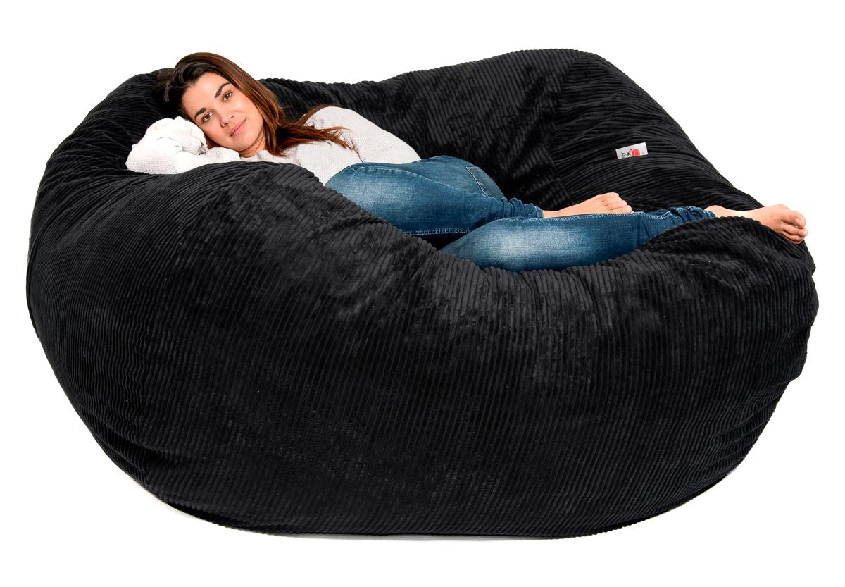 A person relaxing in a large black bean bag chair.