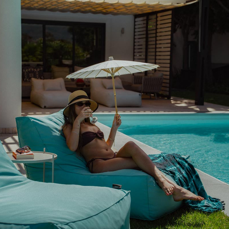 Woman relaxing by a pool with a drink and umbrella