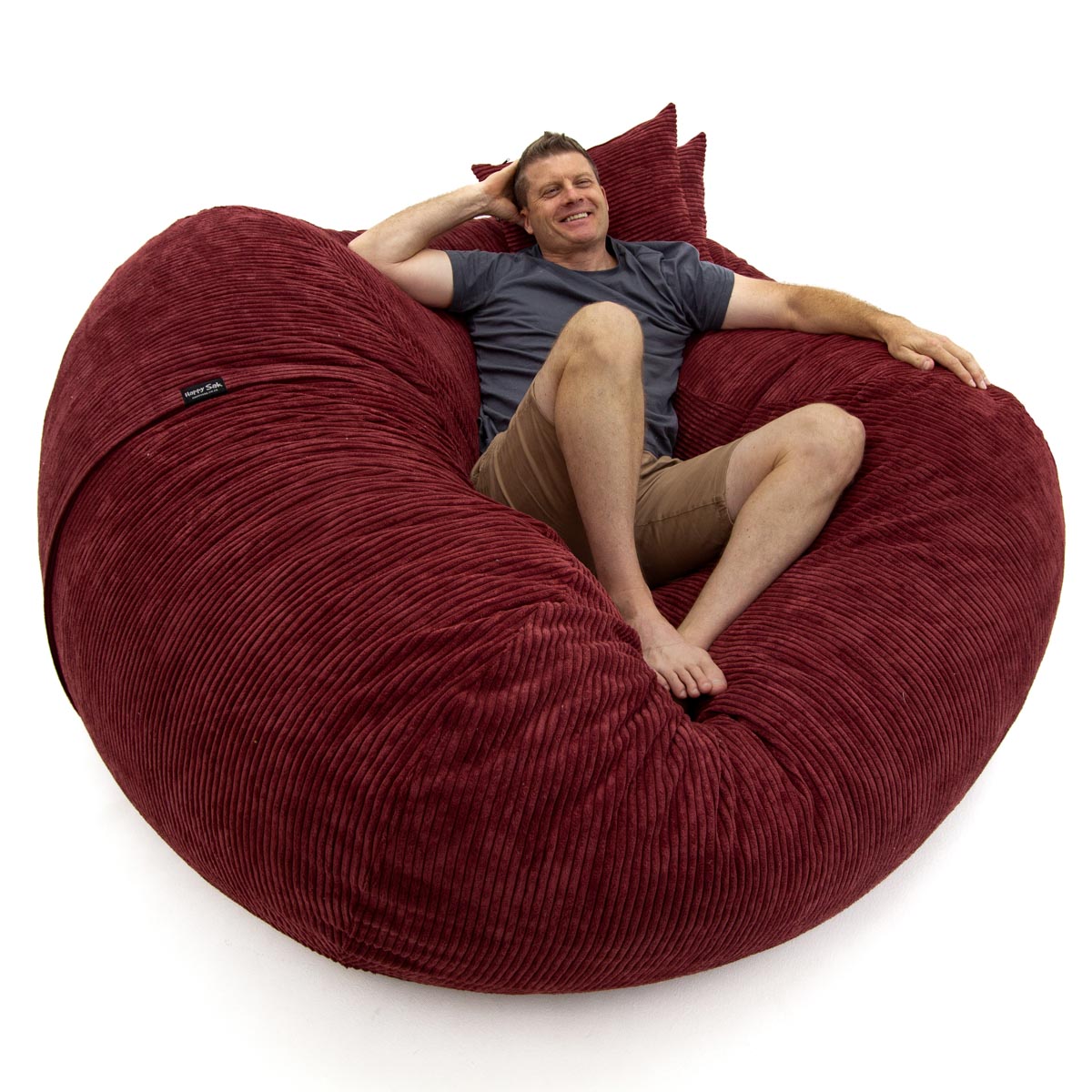 Man relaxing on a large red bean bag chair against a white background