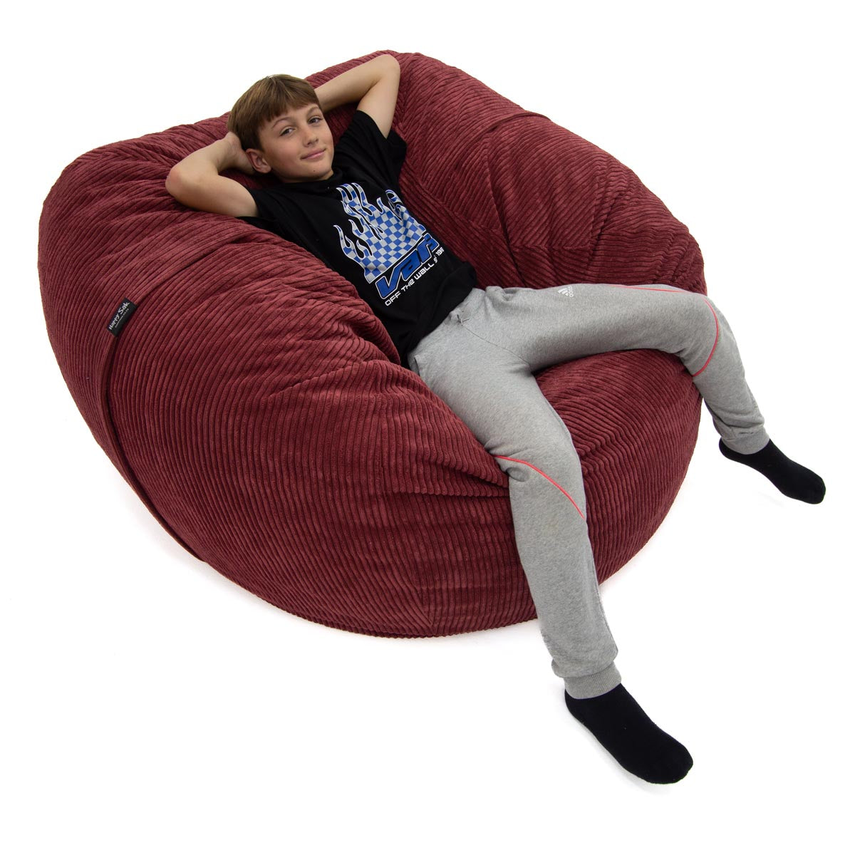 Child sitting on a large red bean bag chair against a white background