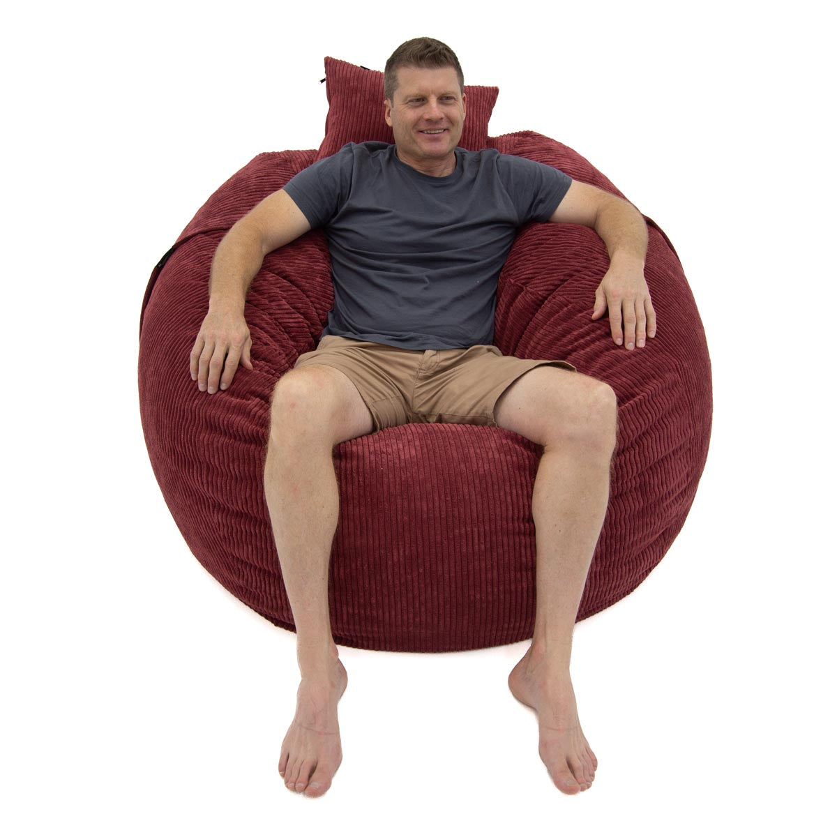 Man sitting on a large red bean bag chair against a white background