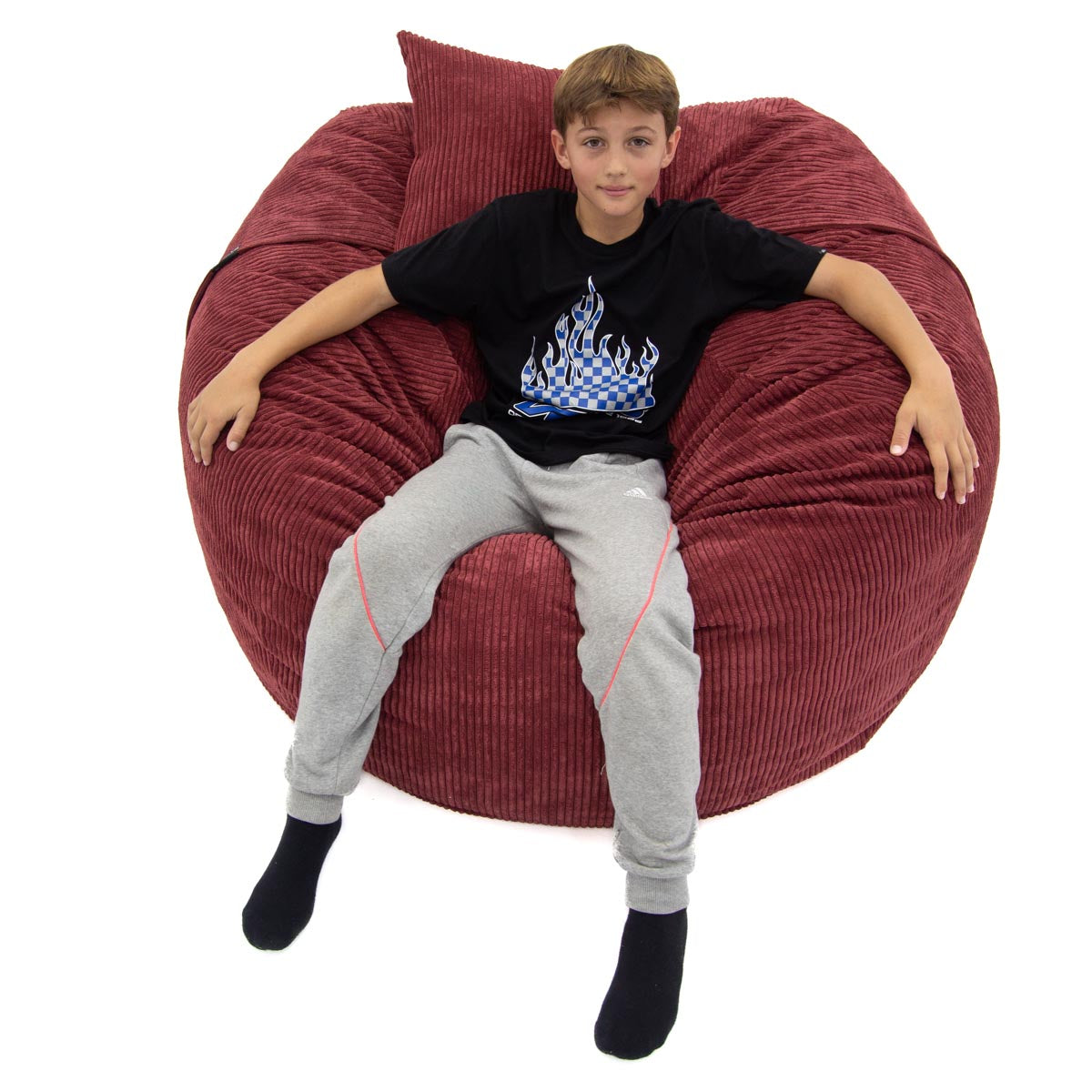 Child sitting on a red bean bag chair with a white background
