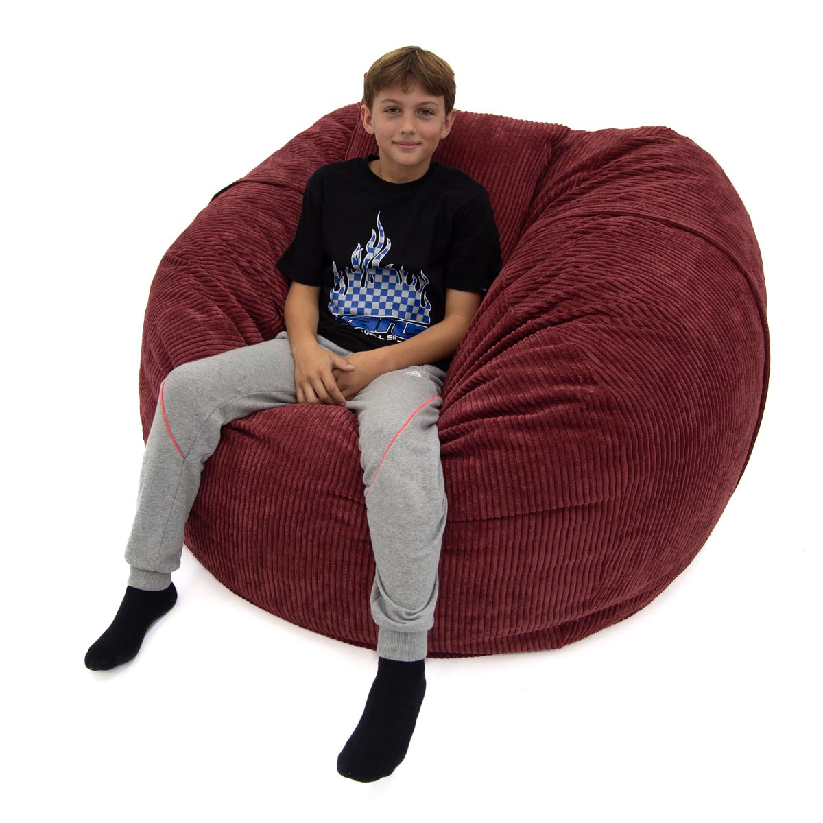 Child sitting on a large red bean bag chair against a white background