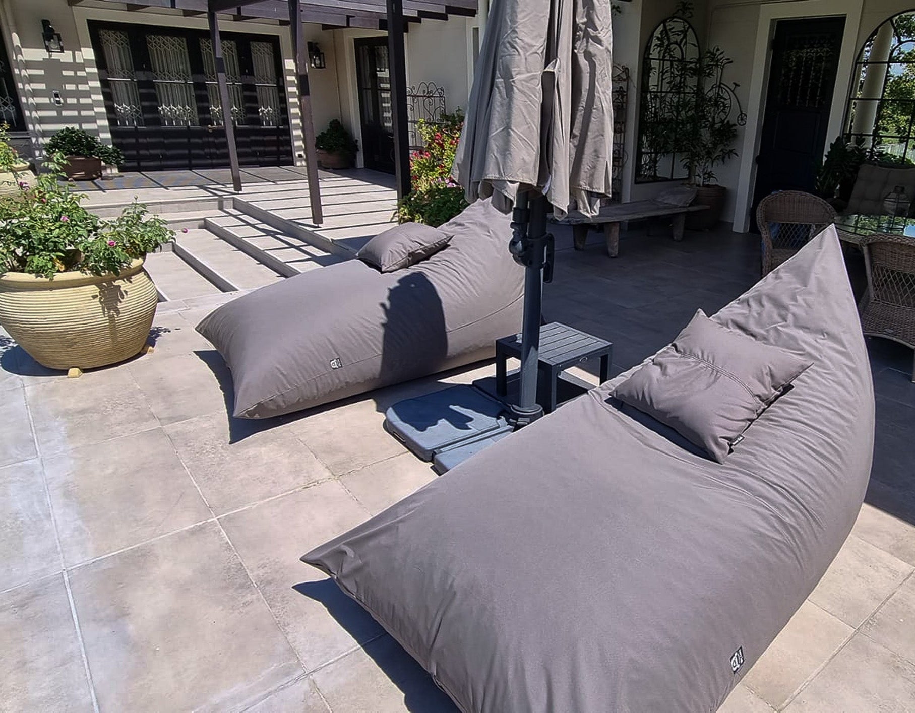 Taupe bean bag chairs on a patio with outdoor furniture and plants.
