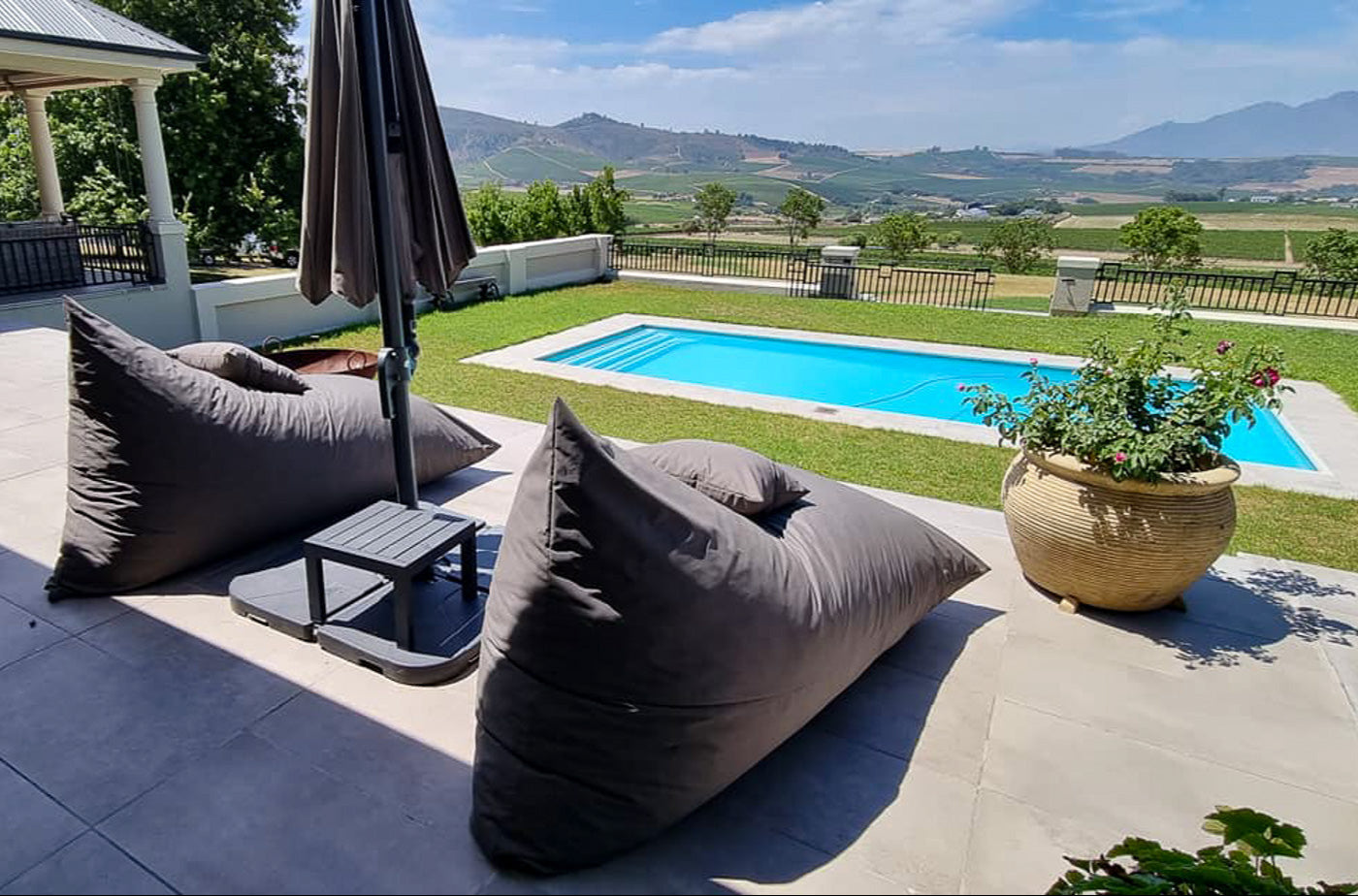 Outdoor patio with bean bags, umbrella, and pool in the background