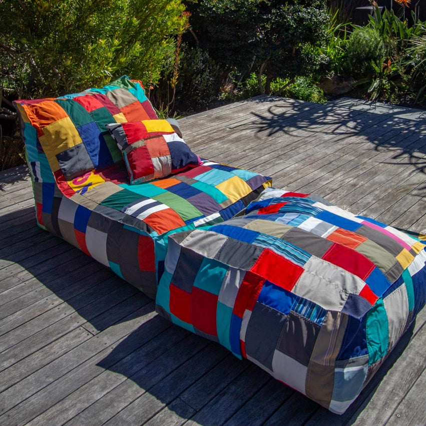 Colorful patchwork lounge chair on a wooden deck with greenery in the background