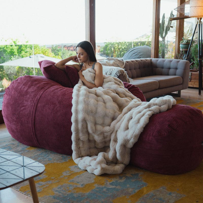 Woman sitting on a large bean bag chair in a modern living room.