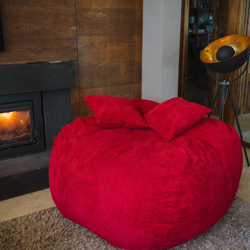 Red bean bag chair in a cozy living room with a fireplace.