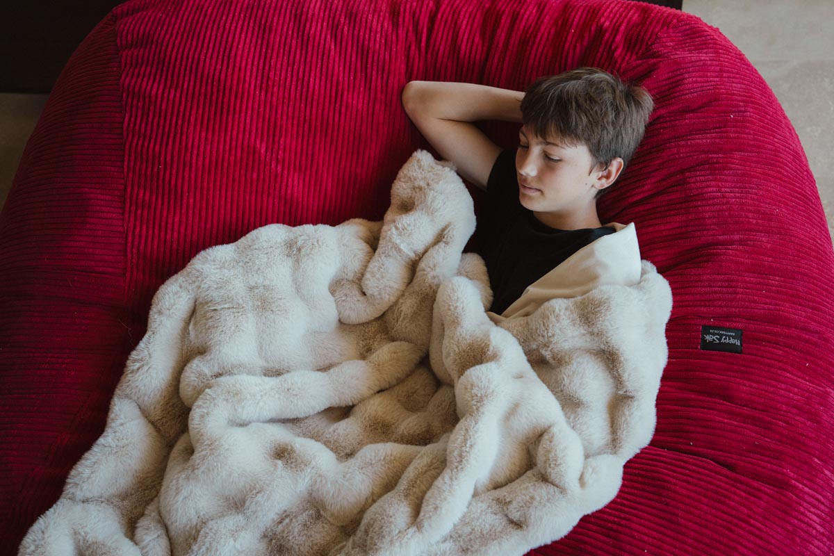 Person wrapped in a blanket on a large red bean bag chair