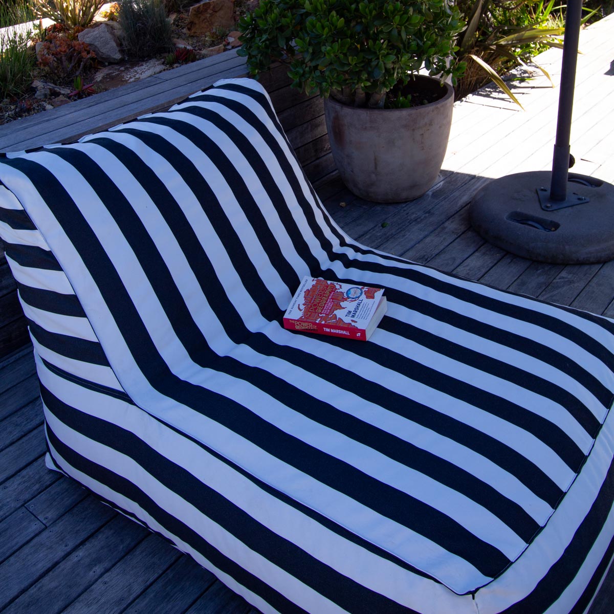 Black and white striped outdoor chair with a book on a wooden deck