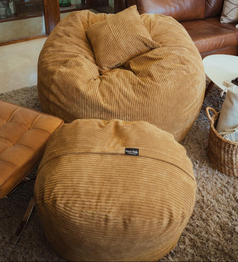 Brown bean bag chairs and ottoman in a room with a couch and plants.