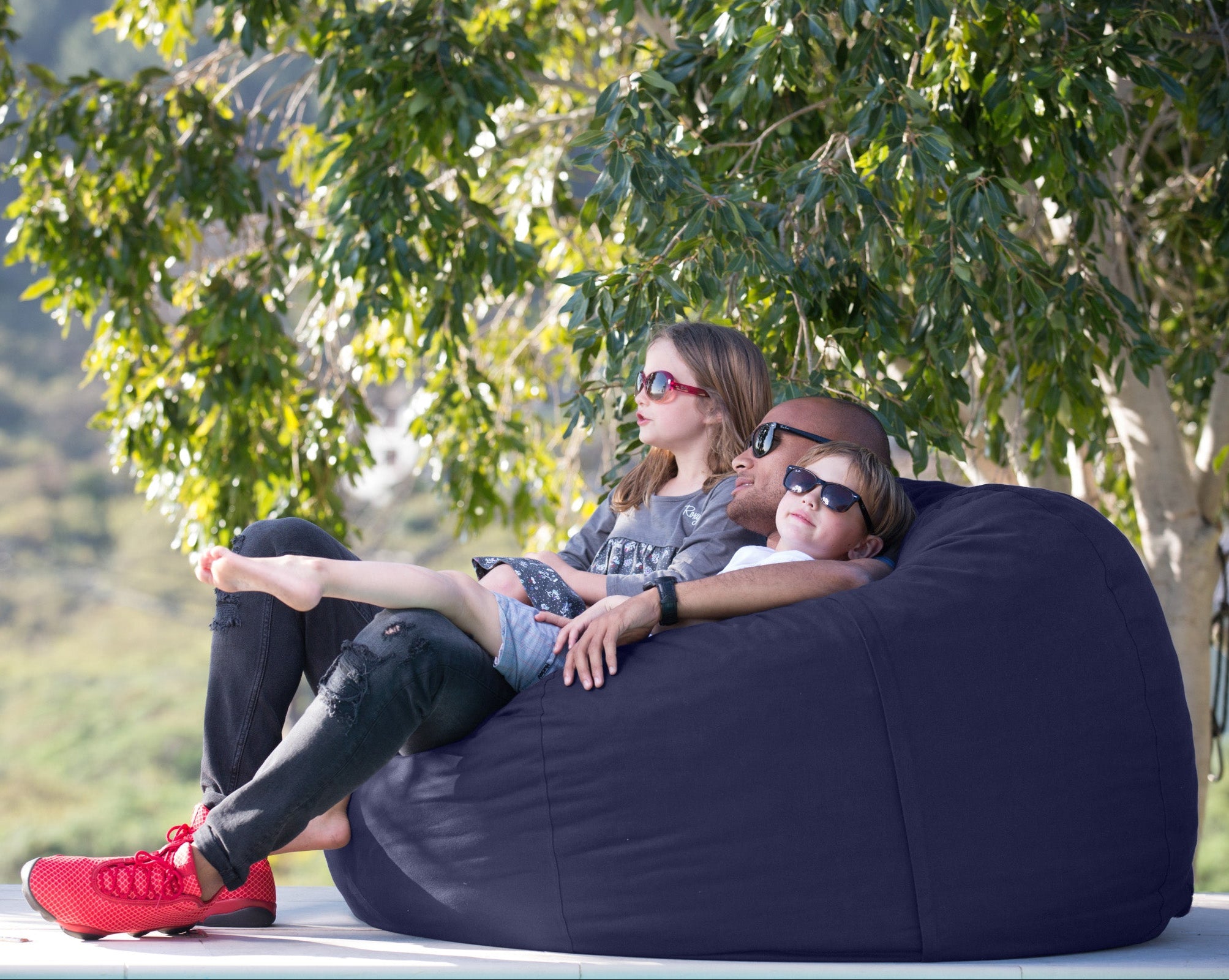 three people sitting on a navy blue outdoor bean bag