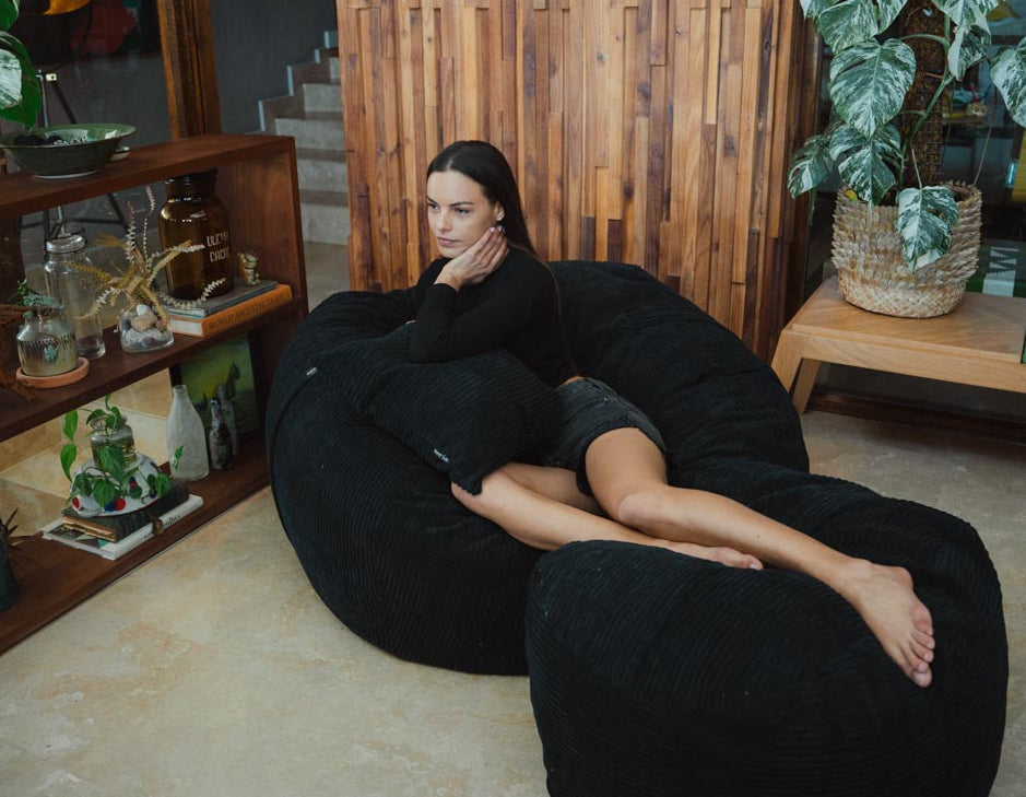 Woman lounging on a black bean bag chair in a cozy living room.