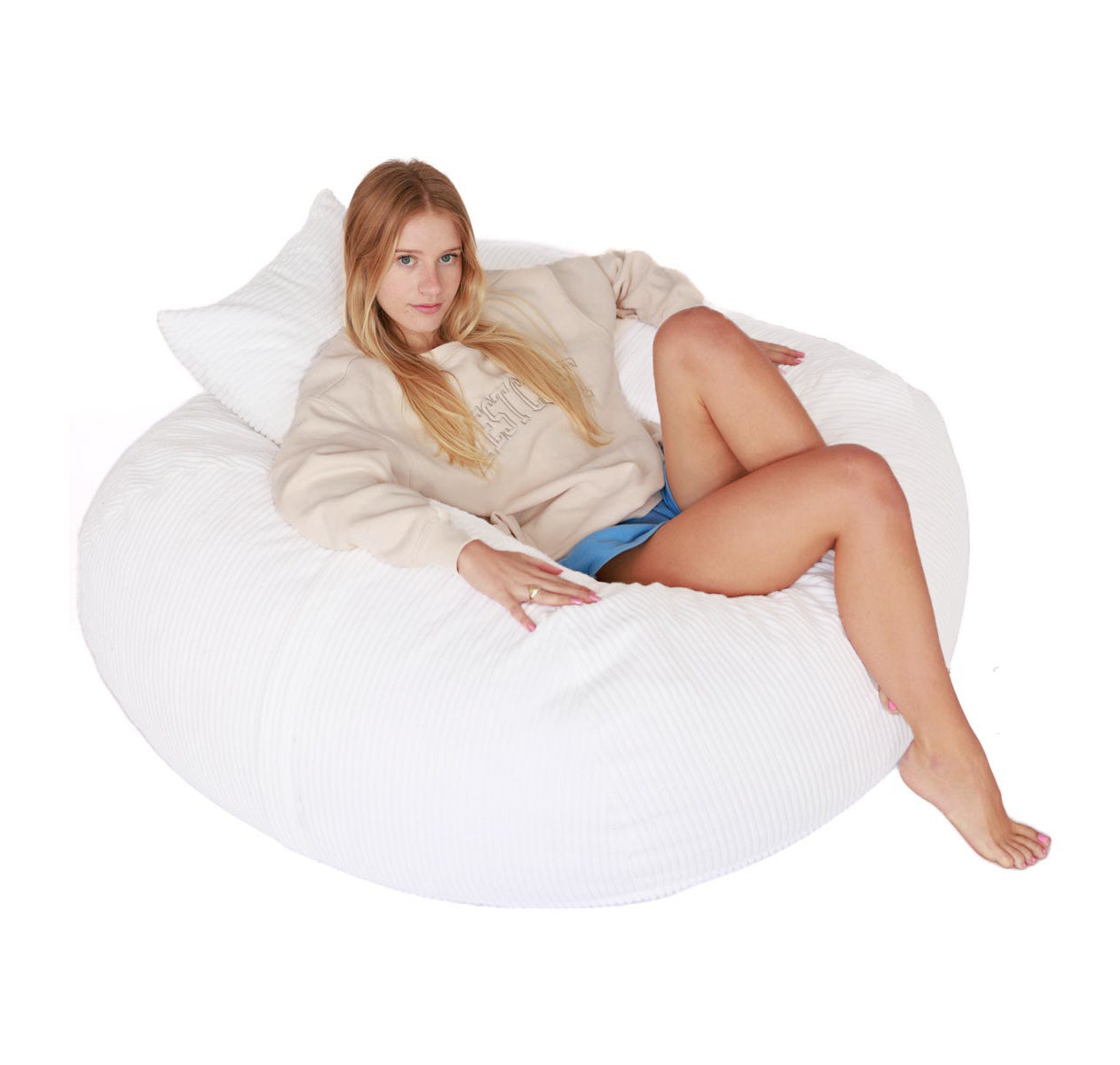 Woman sitting on a white bean bag chair against a white background