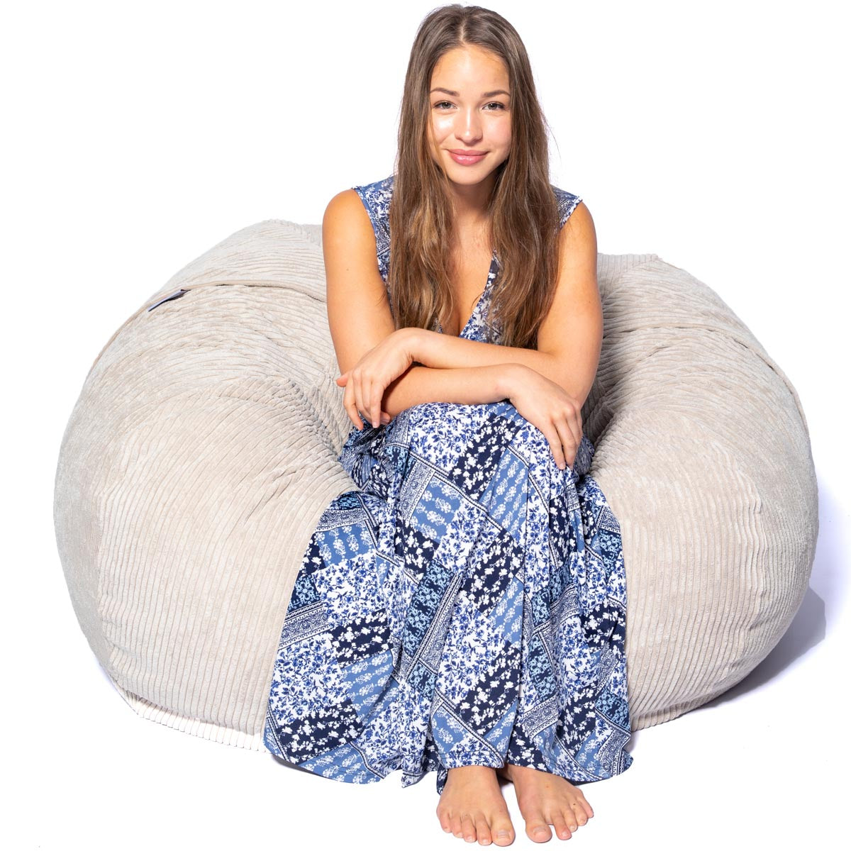 Woman sitting on a large gray bean bag chair against a white background