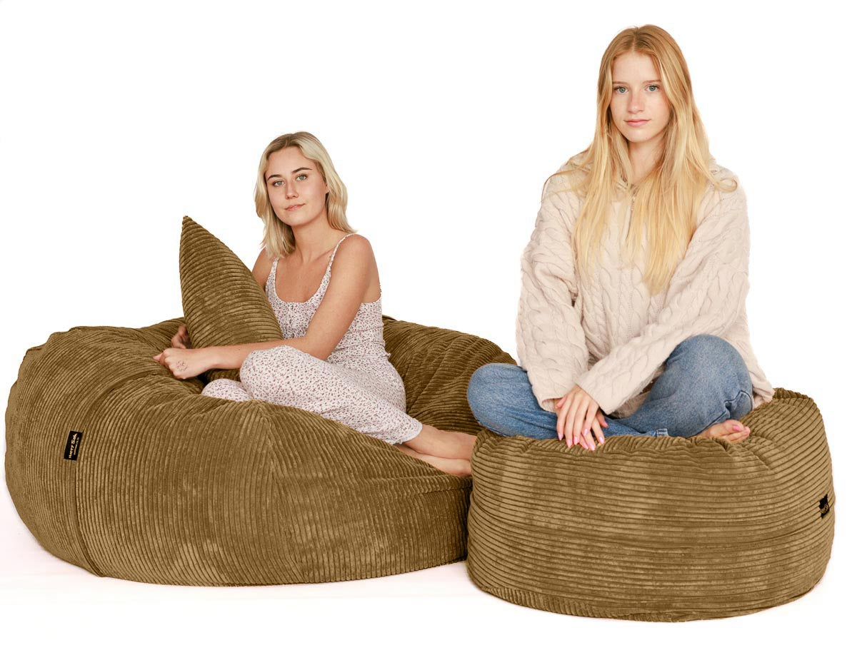 Two women sitting on large brown bean bags against a white background
