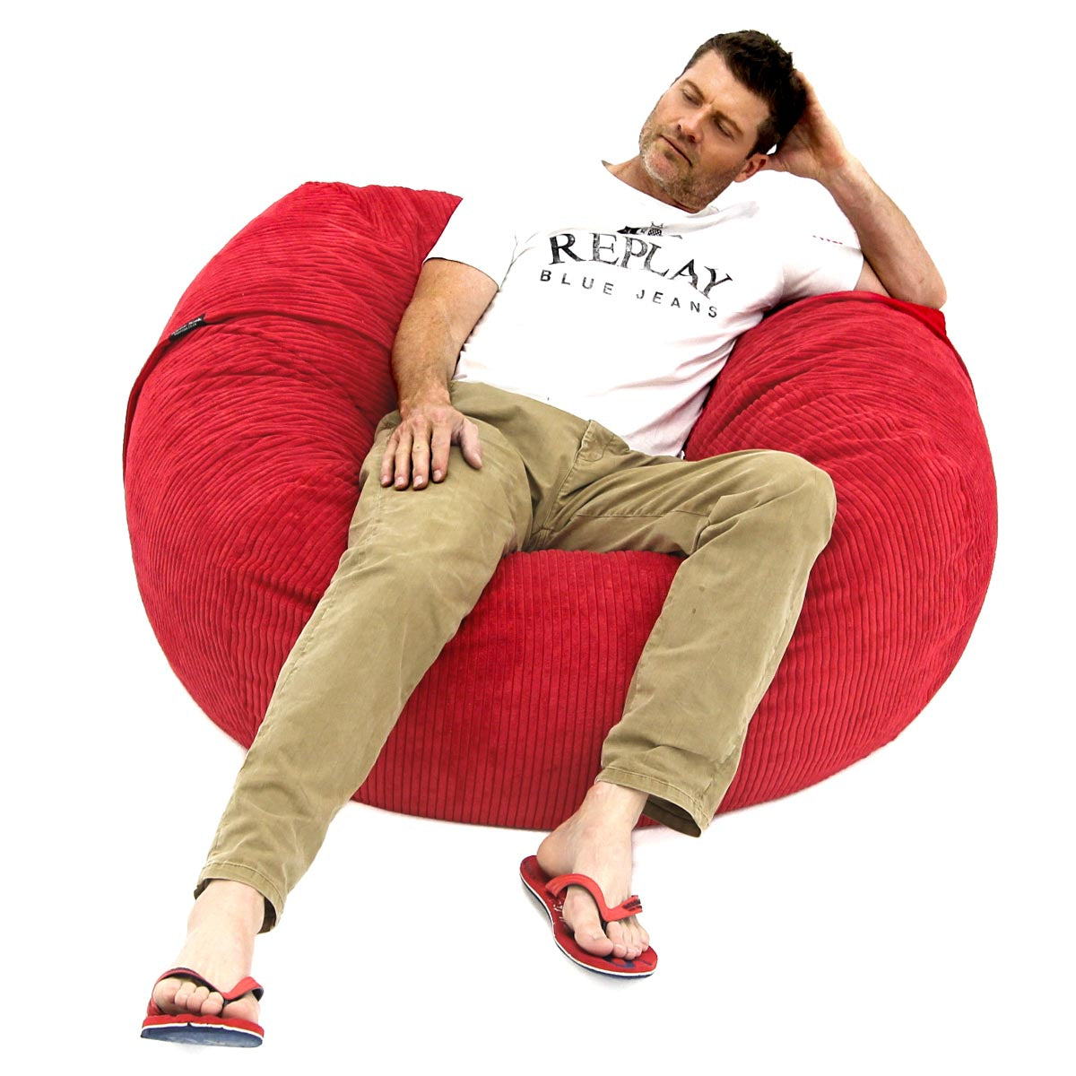 A person lounging on a red corduroy bean bag chair.